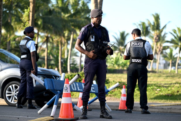 Police officers stand guard at a security check point in Fiji’s capital city Suva on 19 December, 2022. Photo: Saeed Khan / AFP